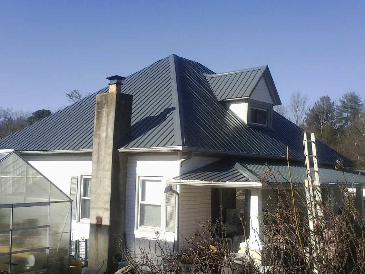 Dark blue standing seam metal roof on a white farmhouse with dormer — Slate & Tile Roof Repair by Roofing Brothers in Joshua