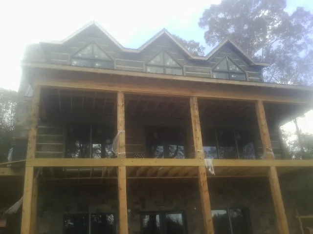 Dormers and porch framing on a large log home under construction — Roof Coating work by our crew in Joshua