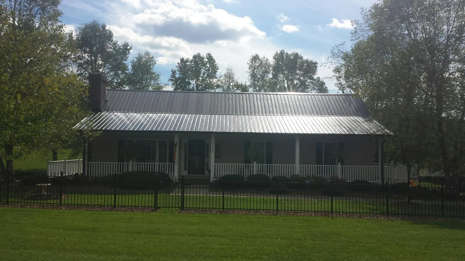 Gray metal roof on a brick ranch with a full width front porch — Gutter Guard Installation work by our crew in Joshua